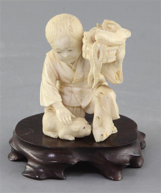 A Japanese ivory okimono of a boy with a dog, Meiji period, height 7.5cm excl. wood stand